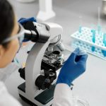 Scientist conducting research in a lab using a microscope and dropper.