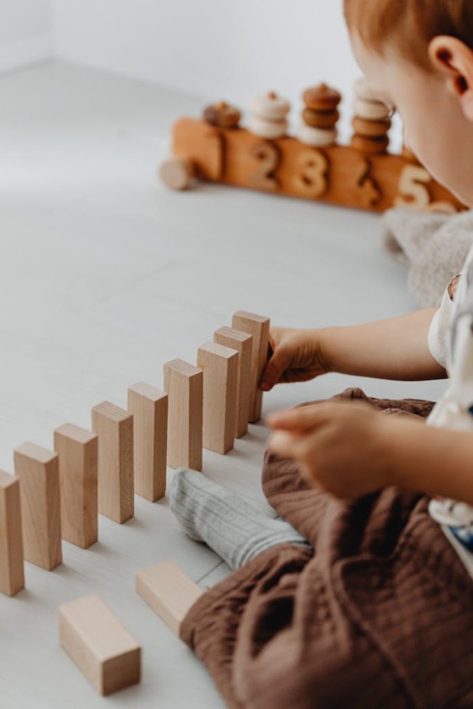 A young child is building with wooden blocks indoors, engaging in creative play.
